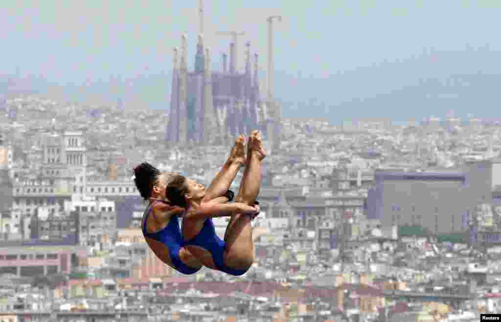 Germany&#39;s Maria Kurjo (R) and Julia Stolle perform a dive during practice for the women&#39;s synchronised 10m platform event, with a backdrop of the Sagrada Familia cathedral, at the Montjuic municipal pool in Barcelona prior to the World Swimming Championships in Barcelona, Spain. 