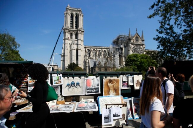 People walk near Notre Dame in Paris, April 19, 2019. The 800-year-old cathedral was devastated by fire this week.