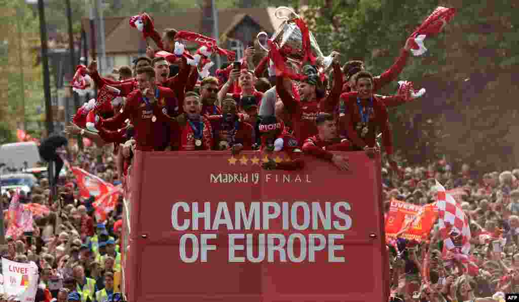 Liverpool&#39;s Spanish defender Alberto Moreno (3R) holds aloft the European Champion Clubs&#39; Cup trophy as he stand with teammates during an open-top bus parade around Liverpool, north-west England, after winning the UEFA Champions League final football match between Liverpool and Tottenham.