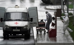 FILE - Medical personnel wearing protective gear move what appears to be a bag containing a human body, outside a hospital for coronavirus patients, on the outskirts of Moscow, Russia May 12, 2020.