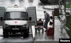 FILE - Medical personnel wearing protective gear move what appears to be a bag containing a human body, outside a hospital for coronavirus patients, on the outskirts of Moscow, Russia May 12, 2020.