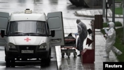 FILE - Medical personnel wearing protective gear move what appears to be a bag containing a human body, outside a hospital for coronavirus patients, on the outskirts of Moscow, Russia, May 12, 2020.
