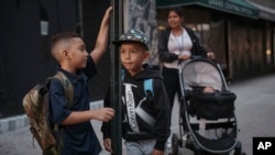 ARCHIVO - Kimberly Carchipulla, a la derecha, y su hijo Damien, de 5 años, en el centro, esperan el autobús camino a la escuela el jueves 7 de septiembre de 2023, en Nueva York.