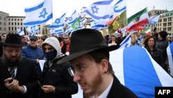 Rabbi Yehuda Teichtal (L) together with demonstrators displaying Israeli flags takes part in a rally in front of the Brandenburg Gate in central Berlin on October 6, 2024, ahead of the one-year anniversary of the October 7 attack on Israel by Palestinian 