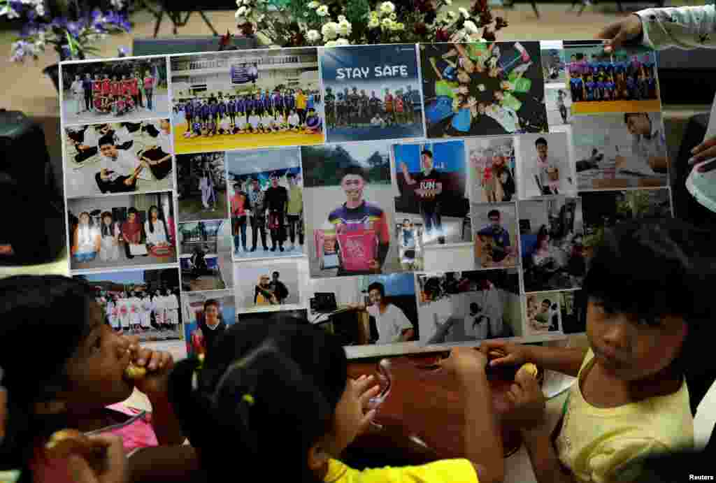 Children look at pictures before relatives and friends pray for the 12 schoolboys and their soccer coach trapped inside a flooded cave, at Mesai Grace Church in the northern province of Chiang Rai, July 8, 2018.