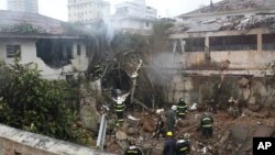 Firefighters work at the crash site of a small plane that was carrying Brazilian presidential candidate Eduardo Campos and several campaign officials, in Santos, Brazil, Aug. 13, 2014. 