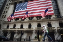A pedestrian wearing a surgical mask and gloves walks past the New York Stock Exchange on March 19, 2020, in New York.