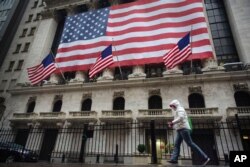 A pedestrian wearing a surgical mask and gloves walks past the New York Stock Exchange on March 19, 2020, in New York.