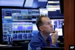 Trader Mark Puetzer works in a booth on the floor of the New York Stock Exchange, March 22, 2018. Stocks fell sharply and bond prices rose after the Trump administration moved to place tariffs on some goods imported from China and restrict Chinese investment.