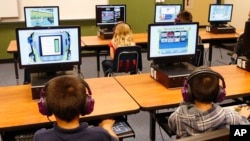 FILE - In this July 21, 2014 file photo, students at a summer reading academy at Buchanan elementary school work in the computer lab at the school in Oklahoma City. President Obama signs sweeping education reforms into law Thursday, giving states and local communities new authority to set standards for students and teachers and limiting the scope of benchmark testing.