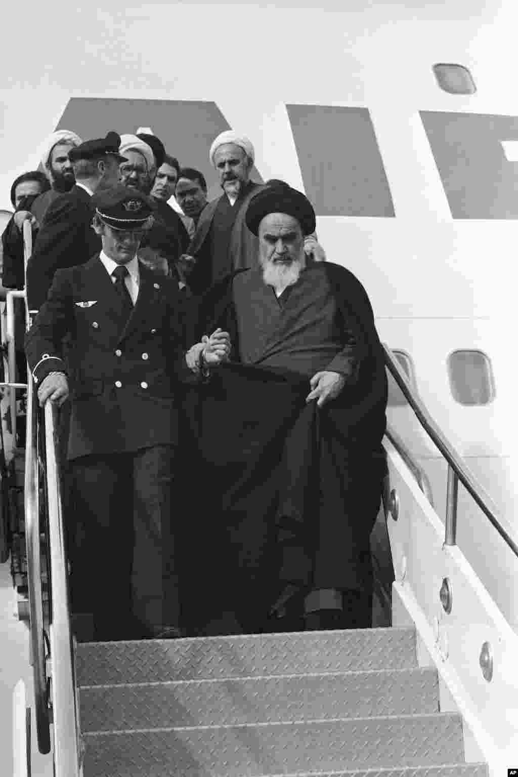 آیت الله روح الله خمینی، رهبر اصلی مذهبی ایران، با کمک خلبانان و خدمه هواپیمای دربست ۷۴۷ از پلکان هواپیما پیاده می شود –فرودگاه مهرآباد تهران، ۱۲ بهمن ۱۳۵۷
