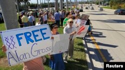 FILE - Protesters hold signs in support of Alan Gross, the U.S. contractor jailed in Cuba for crimes against the state, at a rally for his release in West Palm Beach, Florida, Nov. 11, 2012. 