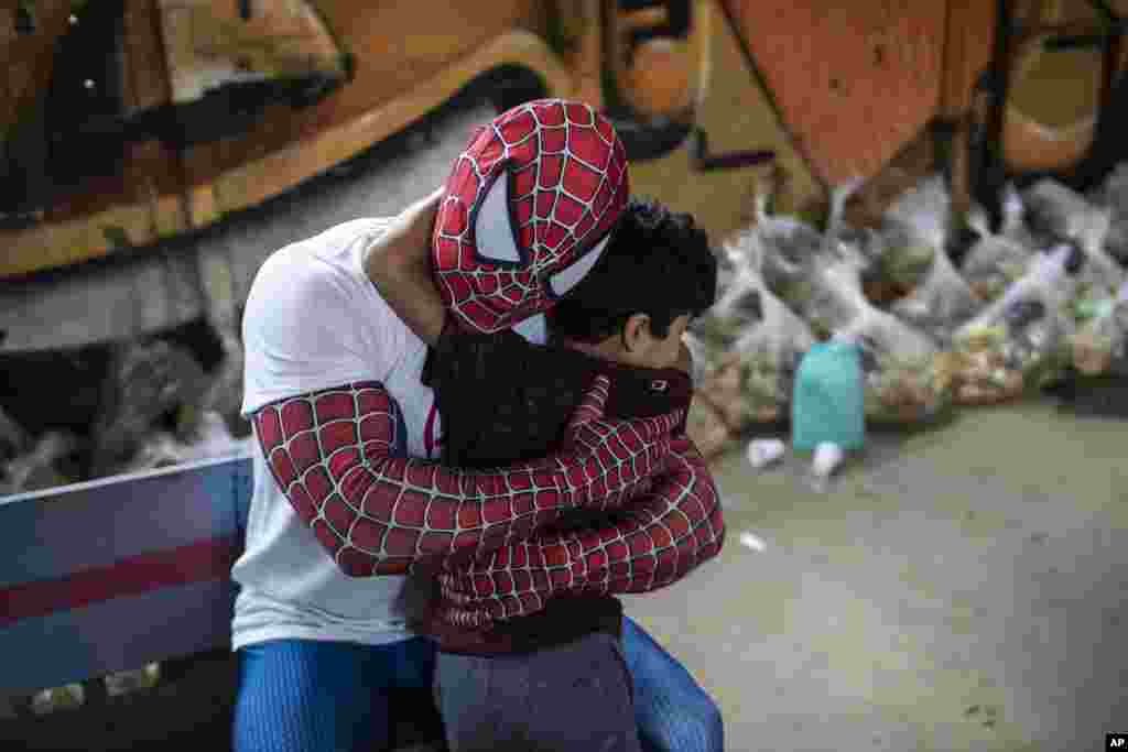 A volunteer dressed as Spiderman embraces a child in the Jardim Gramacho favela of Rio de Janeiro, Brazil, Oct. 30, 2021, during a food kit delivery donated by the non-governmental organization &quot;Covid Sem Fome&quot;.