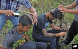 Youths stand in the pond located at a police school, after having their heads shaved by the police, in Aceh Besar of the Indonesia's Aceh province, December 13, 2011.