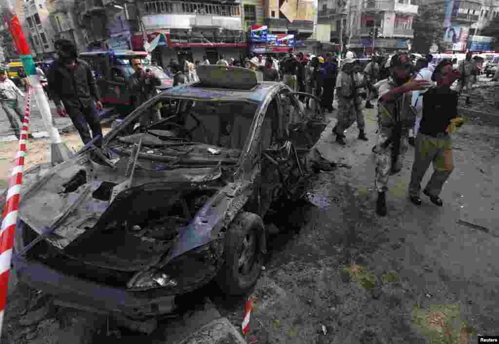 Paramilitary soldiers and police officers direct people away from the site of a bomb blast in Karachi, June 26, 2013. 