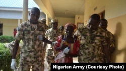 Les forces de sécurité entourent une lycéenne de Chibock sortie de sa captivité avec un bébé en main, dans l’Etat de Borno, 18 mai 2016. 