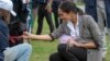 FILE - Meghan, Duchess of Sussex, pats a dog during a visit to a community picnic at Victoria Park in Dubbo, Australia, Oct. 17, 2018. Her Outland Denim jeans quickly sparked a buying fenzy.