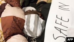 A man sleeps close to a banner reading "We are not safe in South Africa, plz help us to leave this country" where dozens of people camp in a corridor near the offices of the United Nations High Commission for Refugees in Cape Town, Oct. 9, 2019.