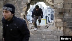 Free Syria Army fighters move through a hole in a wall during a fight with forces loyal to President Bashar al Assad at the front line in Aleppo December 24, 2012.