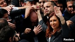 Former Argentine President Cristina Fernandez de Kirchner waves to supporters as she leaves a Justice building where she attended court to answer questions over a probe into the sale of U.S. dollar futures contracts at below-market rates by the central bank during her administration, in Buenos Aires, April 13, 2016.