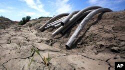 FILE - Irrigation pipes sit along a dry irrigation canal on a field near Stockton, Calif., May 18, 2015.