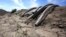 FILE - Irrigation pipes sit along a dry irrigation canal on a field near Stockton, Calif., May 18, 2015.