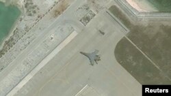 FILE - Satellite imagery shows what the CSIS Asia Maritime Transparency Initiative describes as the deployment of several new weapons systems, including a J-11 combat aircraft, at China’s base on Woody Island in the Paracels, South China Sea, May 12, 2018. (Courtesy CSIS Asia Maritime Transparency Initiative/DigitalGlobe)