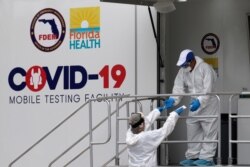 Health care workers work at a walk-up COVID-19 testing site during the coronavirus pandemic, July 17, 2020, in Miami Beach, Florida.