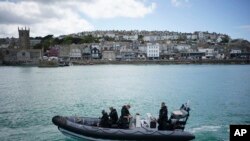 FILE - police officers patrol the harbour in St. Ives, Cornwall, England ahead of the G7 summit that takes place in nearby Carbis Bay.