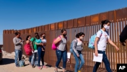 A group of Brazilian migrants walk around a gap in the U.S.-Mexico border in Yuma, Ariz., seeking asylum in the United States after crossing over from Mexico, June 8, 2021.