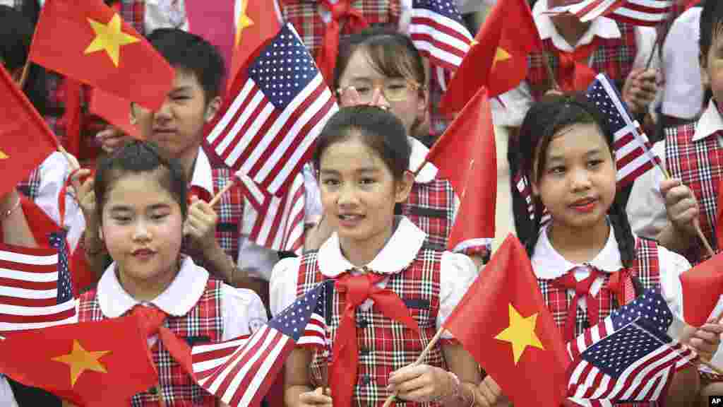 Des étudiants vietnamiens tiennent des drapeaux vietnamiens et américains lors d&#39;une cérémonie pour l&#39;arivée du président américain Barack Obama au Palais présidentiel à Hanoi, Vietnam, le 23 mai, 2016.