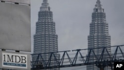 Logo 1MDB (1 Malaysia Development Berhad) di seberang Menara Kembar Petronas di lokasi proyek pembangunan, Tun Razak Exchange di Kuala Lumpur, Malaysia, 8 Juli 2015.