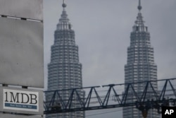 FILE - A 1MDB (1 Malaysia Development Berhad) logo is set against the Petronas Twin Towers at the flagship development site, Tun Razak Exchange in Kuala Lumpur, Malaysia.
