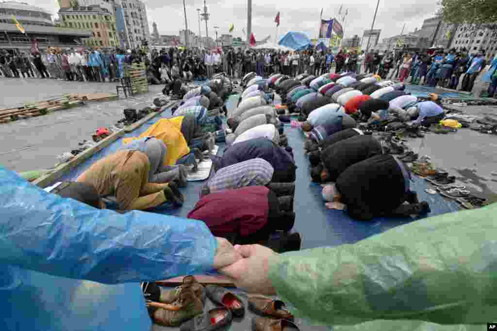 Para pengunjuk rasa saling berpegangan tangan untuk mengisolasi tempat bagi mereka yang melakukan sholat Jumat di Alun-Alun Taksim, Istanbul, Turki. Protes-protes selama dua minggu dan pendudukan di sebuah taman di pusat Istanbul telah mejadi tempat bermulanya krisis politik terbesar dalam 10 tahun pemerintahan Perdana Menteri Recep Tayyip Erdogan. 