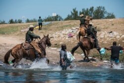 Petugas Bea Cukai dan Perlindungan Perbatasan AS berusaha menghalangi para migran saat mereka menyeberangi Rio Grande dari Ciudad Acua, Meksiko, ke Del Rio, Texas, Minggu, 19 September 2021.