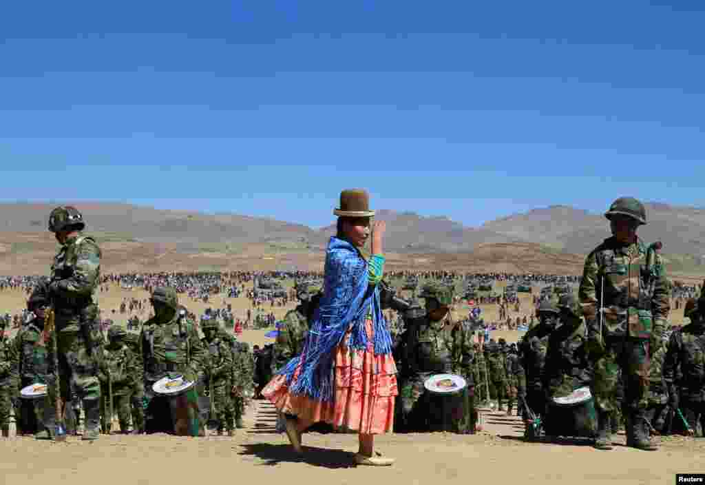 A woman walks in front of a military band during a civil-military parade commemorating the 192nd founding of the Bolivian armed forces in Kjasina, Achacachi, Aug. 7, 2017.
