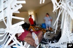 Shaun Vaine, left, and Michele Thrash, right, stand in their destroyed home at the River's Edge apartment complex, May 28, 2019, in Dayton, Ohio, the day after a tornado struck the city.