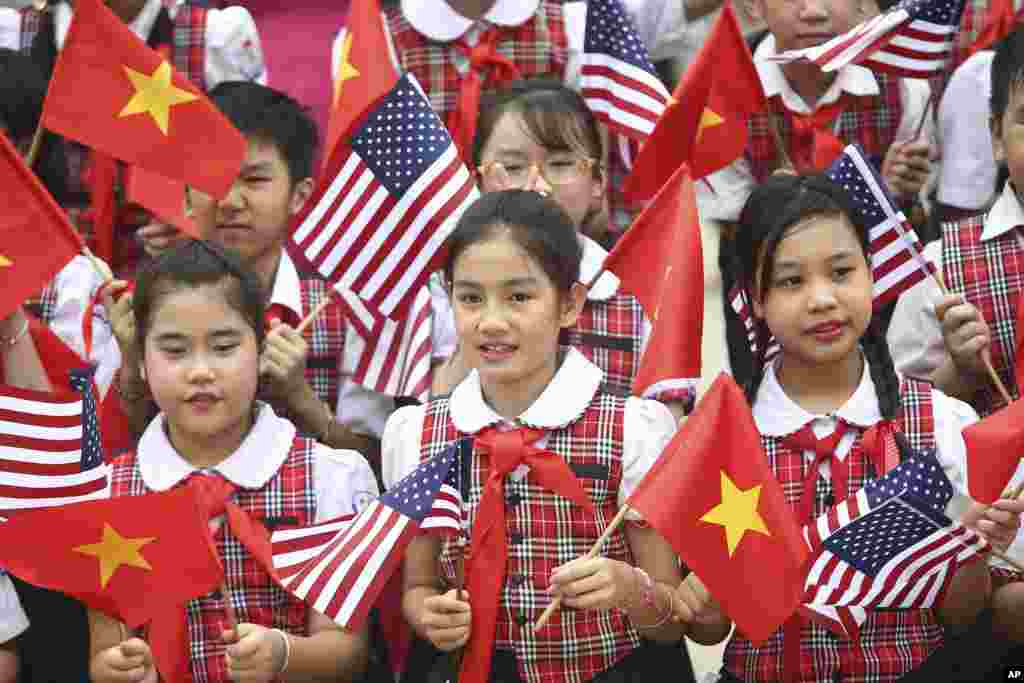 Siswi-siswi Vietnam memegang bendera Vietnam dan Amerika dalam upacara penyambutan Presiden AS Barack Obama di Istana Presiden di Hanoi, Vietnam (23/5). (AP/Na Son Nguyen)