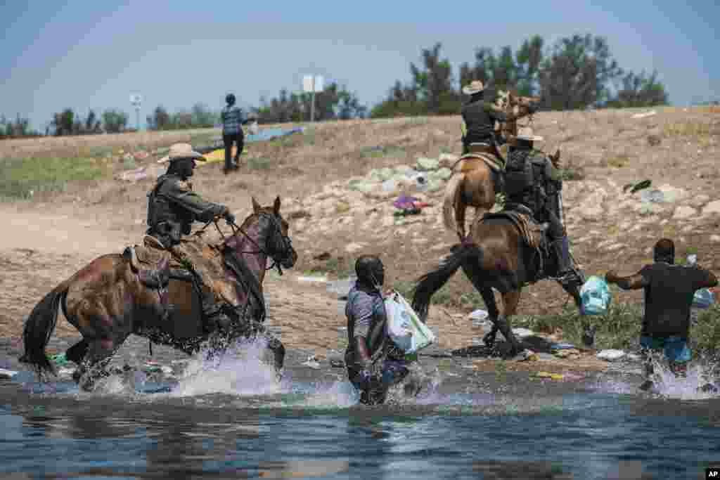 Petugas penjaga perbatasan AS yang berkuda berusaha menahan para migran saat mereka berusaja menyeberangi sungai Rio Grande dari Ciudad Acuna, Meksiko, untuk menuju Del Rio, Texas, AS (foto: AP).