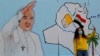 IRAQ - A woman takes selfies with a mural of Pope Francis on the wall of a church upon his upcoming visit to Iraq, in Baghdad, Iraq, February 22, 2021.