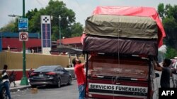 Workers unload coffins from a truck outside a funeral home located in front of the General Hospital in Mexico City on Aug. 20, 2020, amid the COVID-19 coronavirus pandemic. 