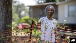 FILE - Jonesville Historic Gullah Neighborhood resident Josephine Wright stands between her home and an orange safety fence that boarders the 29-acre construction site, July 18, 2023,