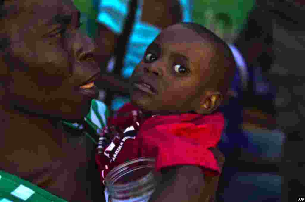 A woman carries a child with symptoms of cholera at the entrance of the St. Catherine hospital in the Cite Soleil neigborhood in Port-au-Prince, Haiti,Thursday, Nov. 11, 2010. Nearly 11,000 people people have been hospitalized for cholera across Haiti wit