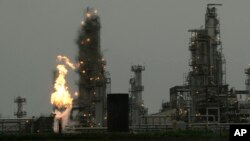 FILE - A Tesoro Corp. refinery, including a gas flare flame that is part of normal plant operations, is shown in Anacortes, Wash., after a fatal overnight fire and explosion, April 2, 2010. Voters in Washington state rejected Initiative 732 in the 2016 election, which called for the nation’s first direct carbon tax on the burning of fossil fuels.