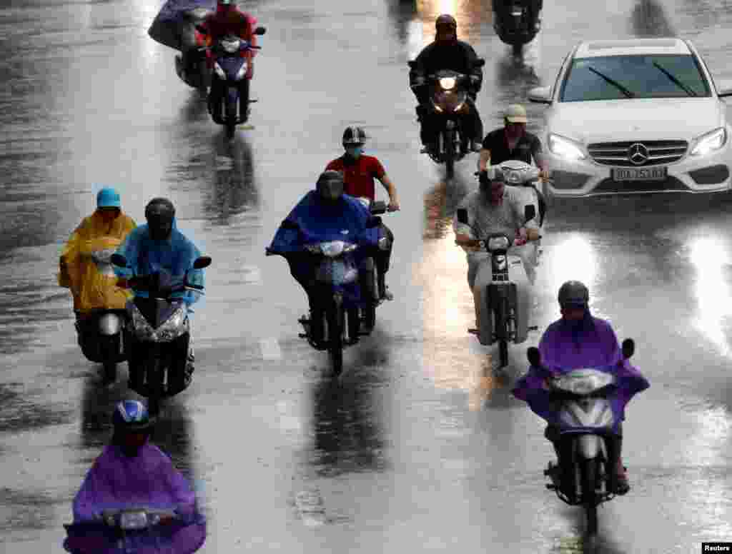 Motorcyclists ride in heavy rain caused by typhoon Dianmu in Hanoi, Vietnam.