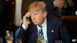 FILE - Donald Trump saat menjadi kandidat presiden dari partai Republik menggunakan telepon seluler saat istirahat makan siang North Charleston, S.C., 18 Februari 2016. Presiden Trump melalui Twitter pada 29 Juli 2017 mengkritik para senator. (Foto:Dok)