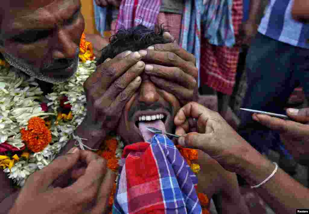 The tongue of a Hindu devotee is pierced with a metal skewer during the annual Shiva Gajan religious festival in Banga village in West Bengal, India. Hundreds of faithful devotees offer sacrifices and perform acts of devotion during the festival in the hopes of winning the favor of Hindu god Shiva and ensuring the fulfillment of their wishes, and also to mark the end of the Bengali calendar year.