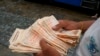 En esta imagen de archivo, tomada el 5 de agosto de 2021, un hombre cuenta billetes por el equivalente a un dólar en una parada de autobús en Caracas, Venezuela. Foto AP.