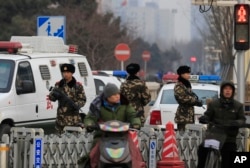 Armed Chinese paramilitary policemen stand guard in the capital city's popular shopping and tourist area of Wangfujing in Beijing, Dec. 27, 2015.