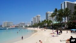 In this Monday, March 13, 2017 photo, people relax on the beach in Waikiki in Honolulu. (AP Photo/Caleb Jones)